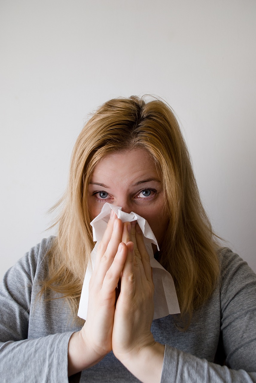Woman sneezing into a tissue