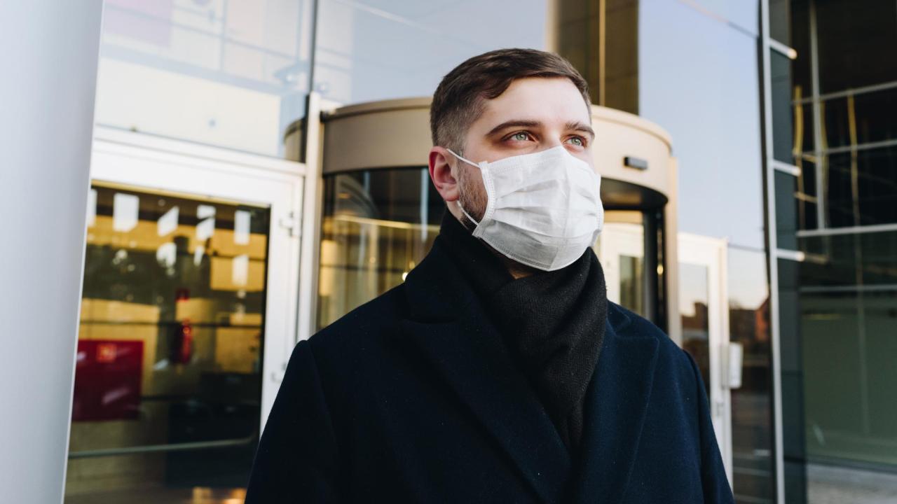 Man wearing a face mask in front of a building