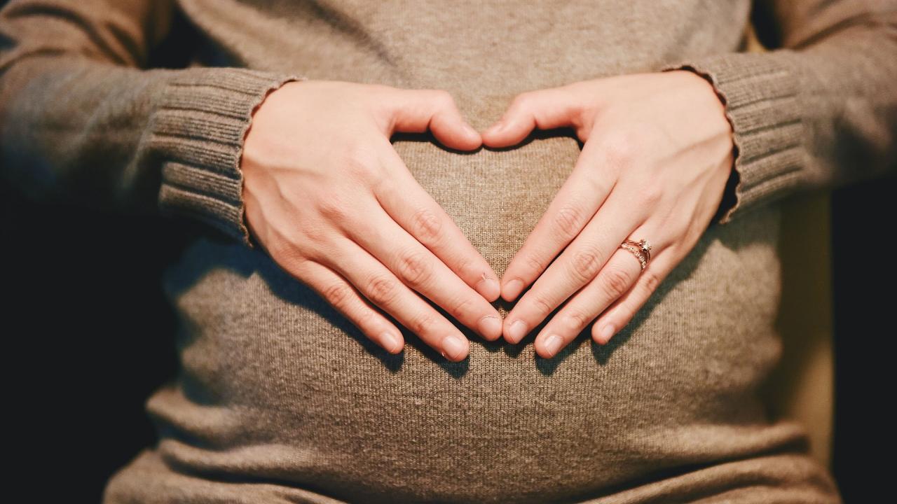 Hands making heart shape on pregnant belly