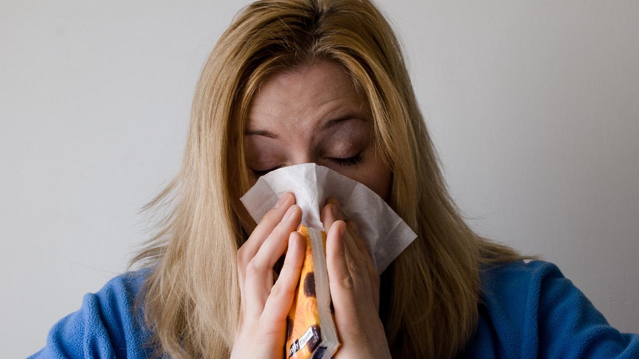 Woman sneezing into tissues