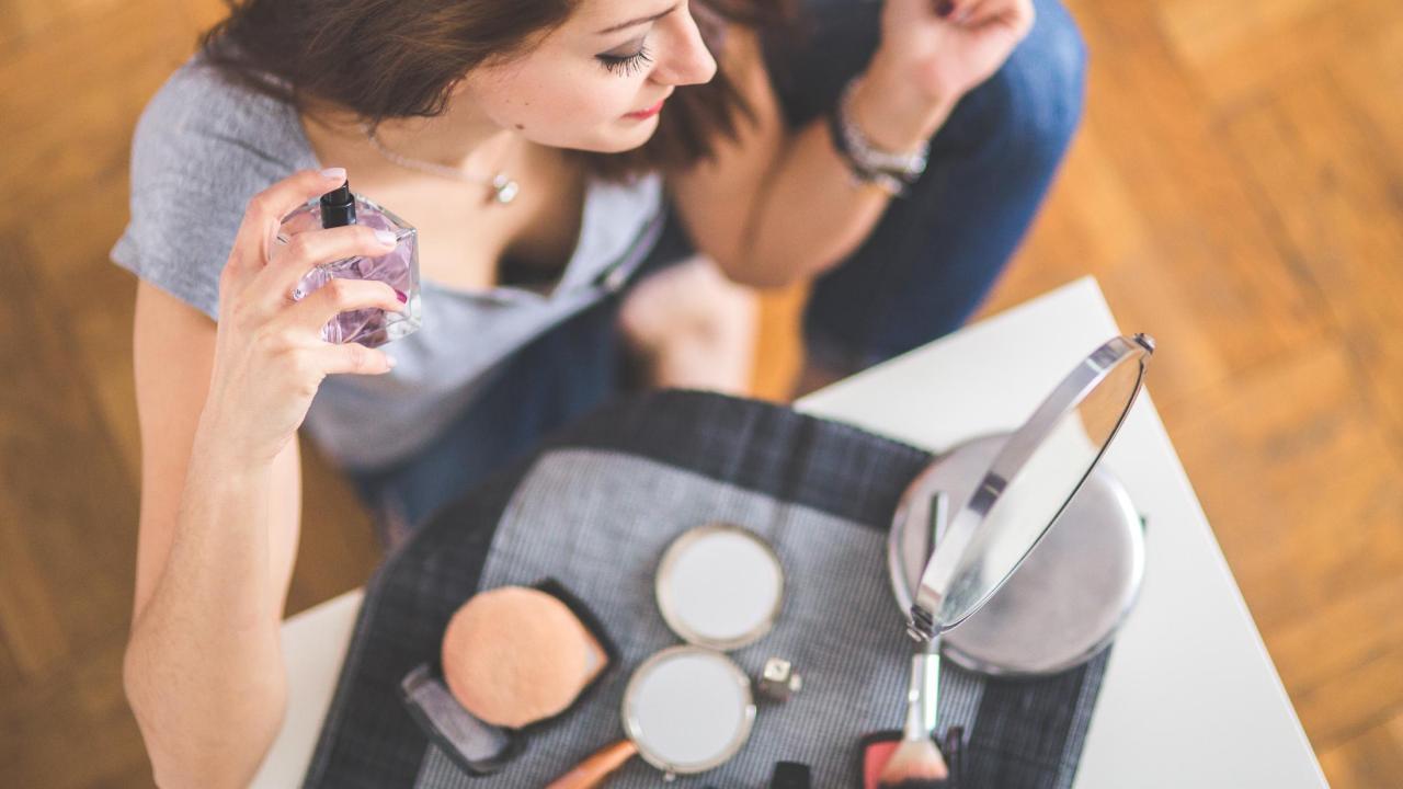 Young woman spraying perfume on neck