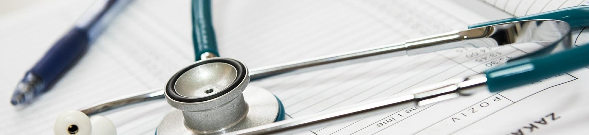 Stethoscope and pen atop medical papers