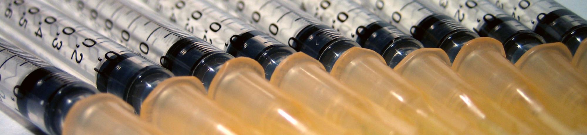 Needles and syringes lined up on a table